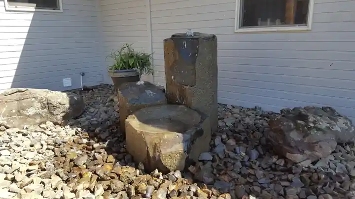 Basalt column fountain with a carved stone basin beside a house, set in gold rock
