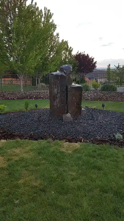 Three basalt columns in a black rock bed on a lawn