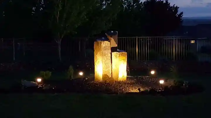 Two basalt columns uplit at night in a dark garden