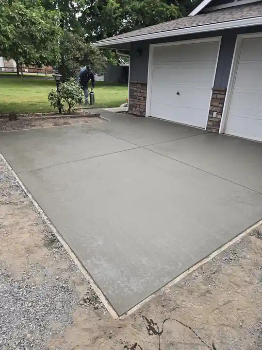 Freshly poured concrete driveway pad in front of a two-car garage
