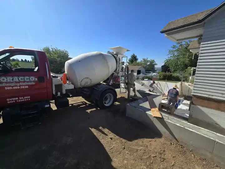 Red Soracco mixer truck pouring into foundation forms alongside a house