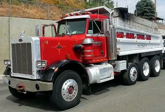 Red Peterbilt dump truck lettered sand, gravel, topsoil, bark