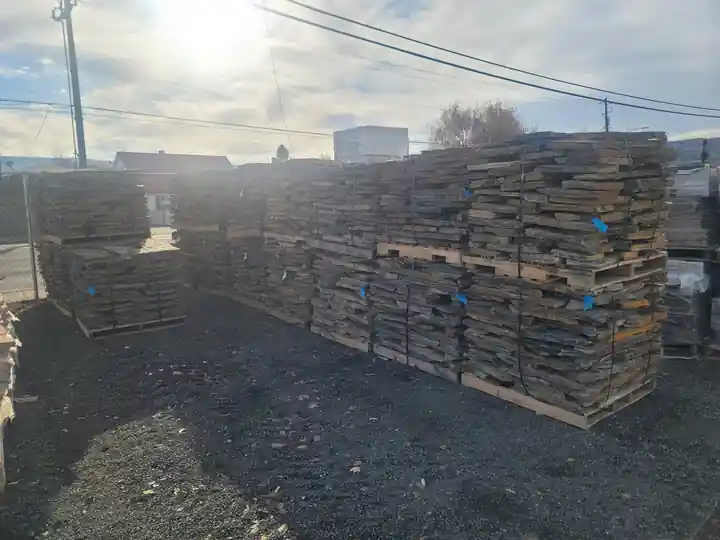 Flagstone pallets stacked in the Soracco yard, backlit by low winter sun